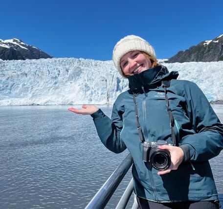 Ellie Miller standing on deck of a boat in front of a glacier
