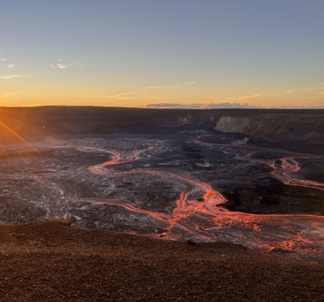 Color photograph of lava flowing in volcanic crater at sunrise