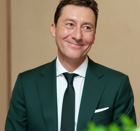 A headshot of a smiling man in a suit