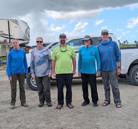 five people stand for a group shot in front of a truck