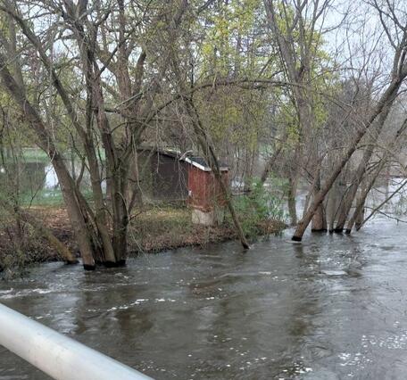 Red streamgage housing on banks of a flooded river