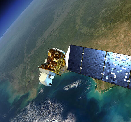 A white and gold satellite with blue solar panel attached orbits above the Earth