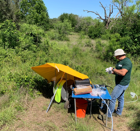 Image of man with water sample near a mobile lab in a open forest