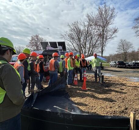 Alton Anderson of the USGS explaining common geophysical tools used to evaluate boreholes to a group of people at a worksite.