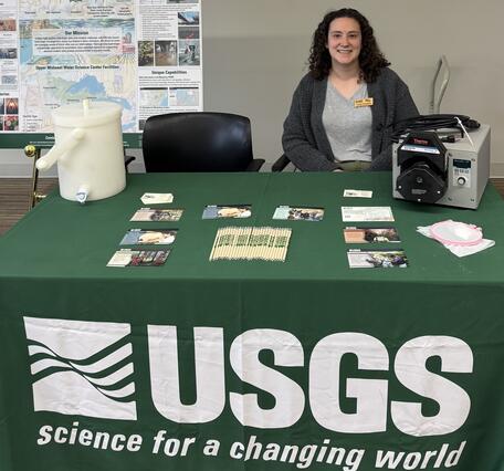 Hydrologist sits behind a USGS table at a career fair