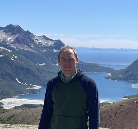 white man in front of a mountain and lake
