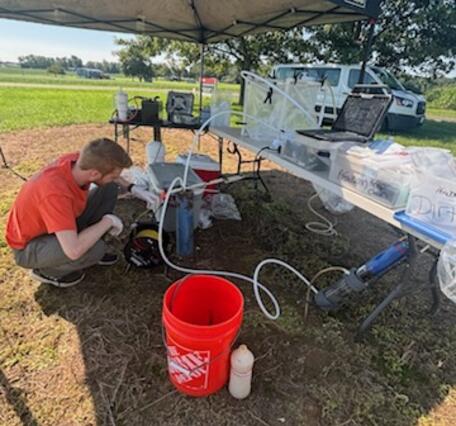 Scientist setting up sampling pump in well pipe.