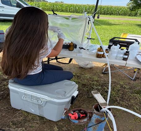 Scientist collecting groundwater samples in a sealed workspace while in the field