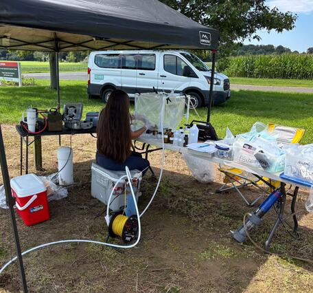 USGS Scientist collecting groundwater samples within a protective housing in the field