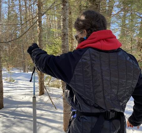 Pulling up a blue tube out of a white PVC pipe in the ground in the winter.