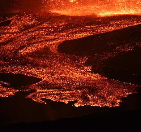 Color photograph of lava flows at night 