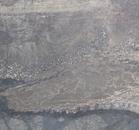 Color photograph showing cold lava flows that are getting close to a damaged road