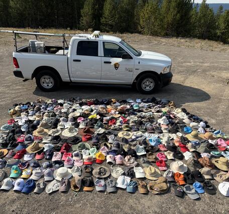 Hundreds of hats laid out for display with a truck in the background providing a sense of scale