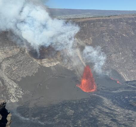 Color photograph of vent erupting on side of crater