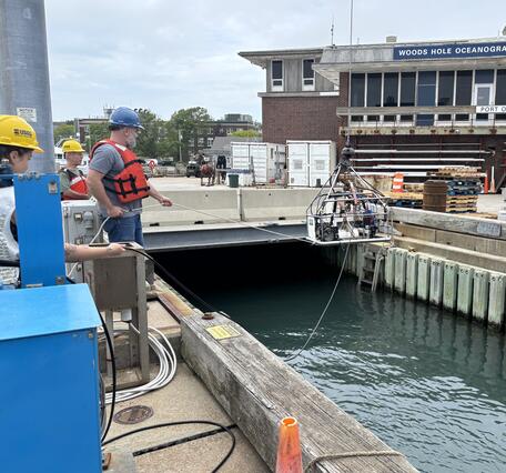 Equipment being lowered into the water by people on a dock