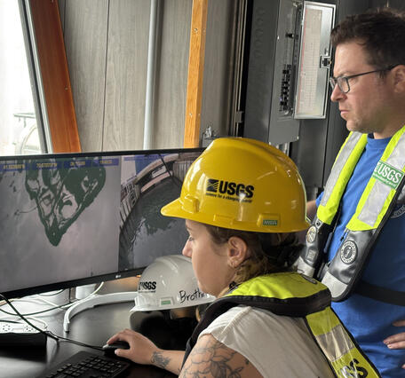 two people looking at two side-by-side computer screens