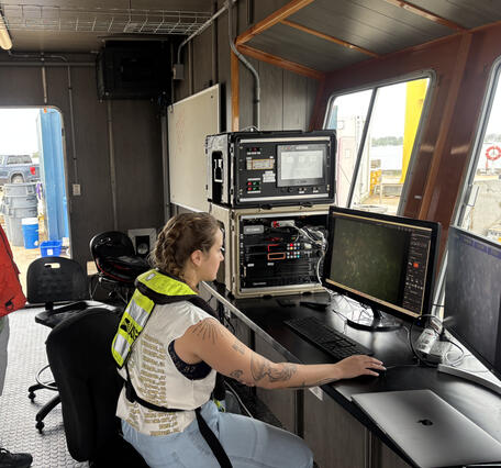 Three people staring at computer screens showing images of the seafloor