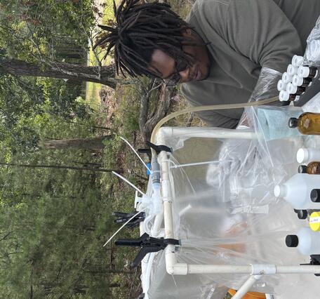 Scientist sitting at a field table working with samples inside a clean chamber