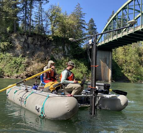 two men on a whitewater cataraft traverse green river water
