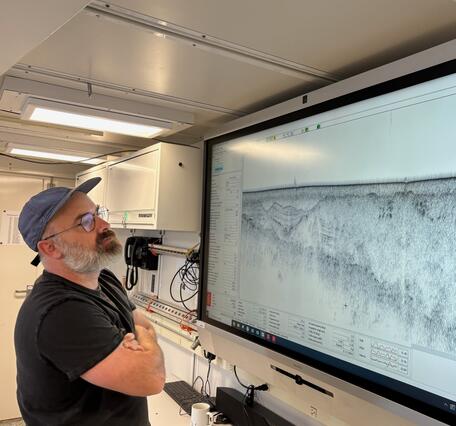Man looking at a subbottom profile data on a large screen