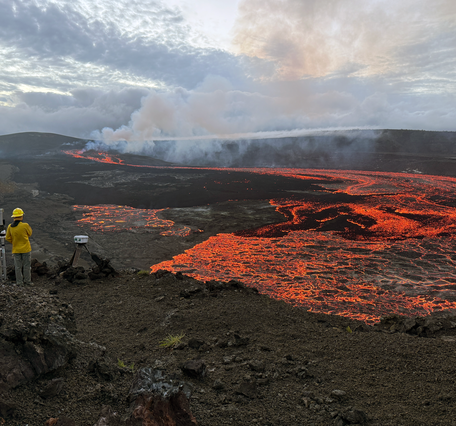 Red, incandescent lava flows cover a large portion of a crater floor