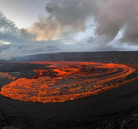 An incandescent red lava flow covers a large area of a crater floor