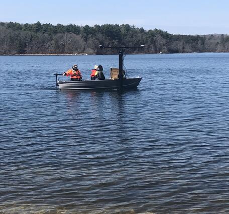 small boat on pond with trees in the background