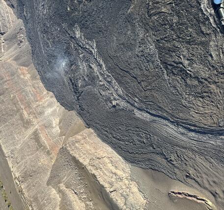 Color photograph of solidified lava channel next to crater wall