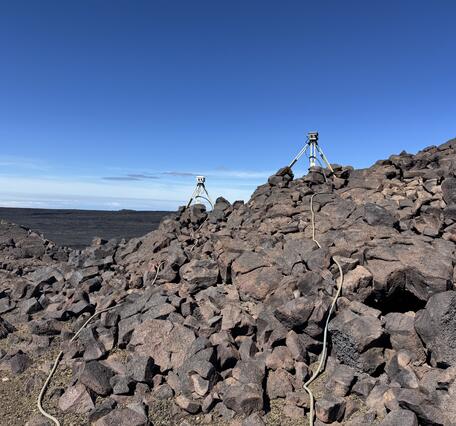 Color photograph of volcano monitoring equipment on lava flows