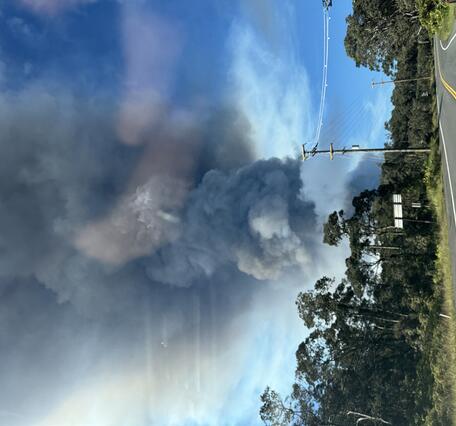 Color photograph of a volcanic plume rising above a highway