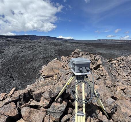Color photograph of volcano monitoring webcam located on a lava flow near a crater edge