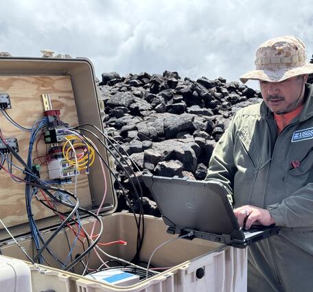 Color photograph of field engineer servicing a remote volcano monitoring site