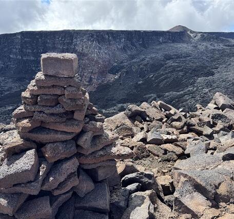 Color photograph of trail cairn near volcanic caldera