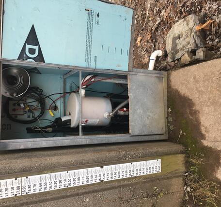 Looking at scientific equipment inside a steel shelter set against the back of the gage house