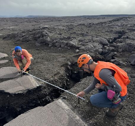 Color photograph of two scientists measuring a crack in a road