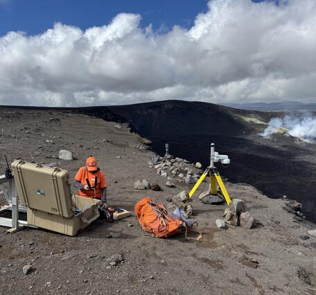 Color photograph of scientists deploying webcamera on volcano