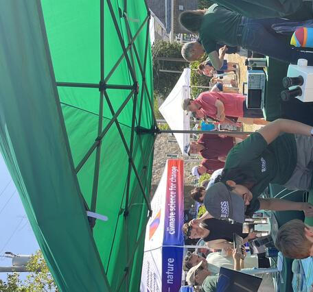 person behind USGS booth talking to adult and child outside under a tent
