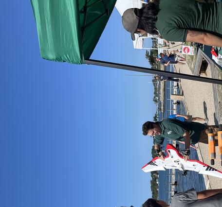 USGS scientist holding drone outside showing it to a group of people