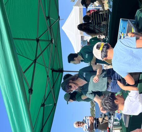 Person in USGS shirt talking to adult and two kids at USGS booth outside