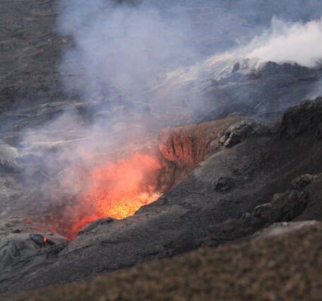 Color photo of lava spattering out of the north vent. The lava appears orange due to it's high temperature. 