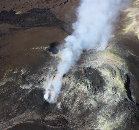 Color photograph of volcanic eruptive vents emitting a gas plume