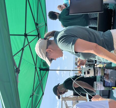 USGS scientist talking to person outside at a USGS booth under a tent