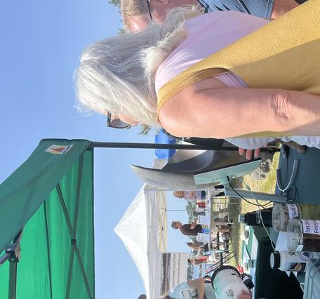 person showing equipment to visitor at USGS booth under tent outside
