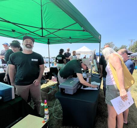 USGS scientists talking to visitors at booth under tent outside