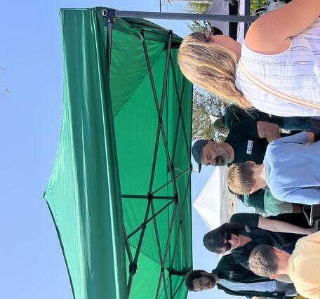 people visiting USGS booth outside under tent