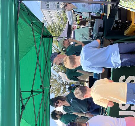 USGS scientists standing behind booth while kids play with Legos on the table