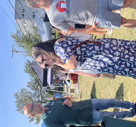 Two people talking to USGS scientist referencing computer monitor on table outside