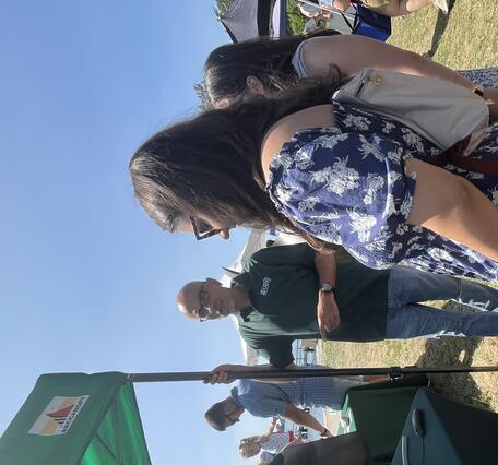 person in USGS shirt standing next to USGS booth and tent, talking to two people referencing a computer monitor