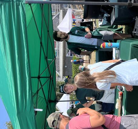 Man and child talking to USGS scientist at booth under tent outside