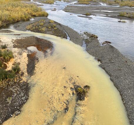 Pale orange river entering clear blue river.